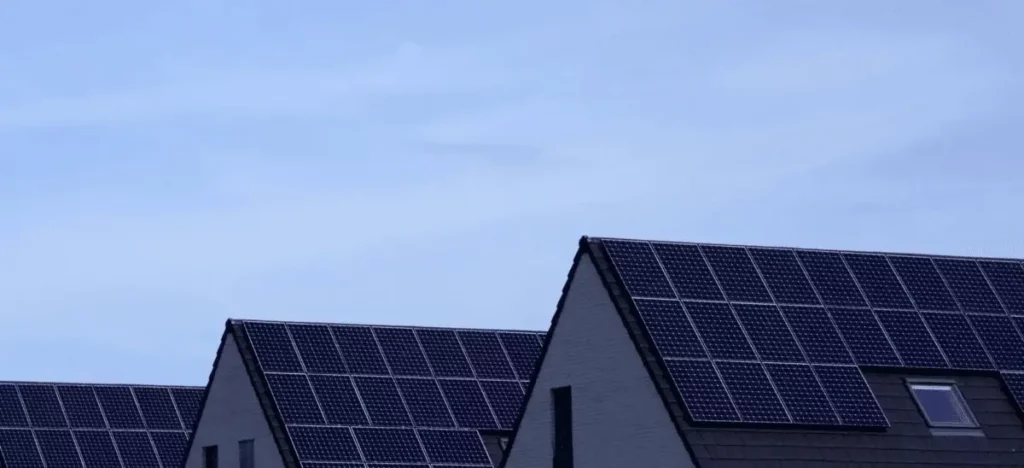 Multiple solar panels installed on the roofs of three houses, maximizing solar energy generation.