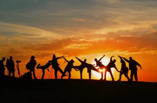 Group of people enjoying the evening, silhouetted against the setting sun.